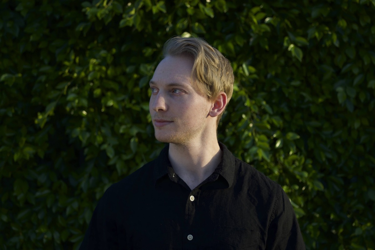 Cody Hergenroeder standing in front of green foliage